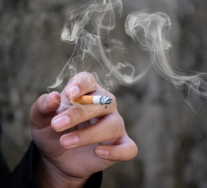 Closeup hand holding lighted cigarrette of asian smoking boy in private area of school and house to avoid punishment from teachers or parents, new edited.