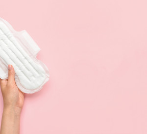 Female hand with menstrual pad on pink background